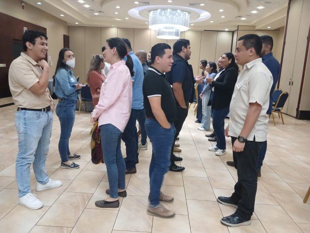 The participants stand in lines, They each stand face-to-face with a partner, engaging in dialogue. 